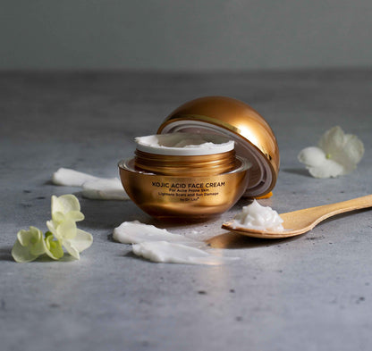 Amber face cream jar with gold cap tipped open, showing white cream inside