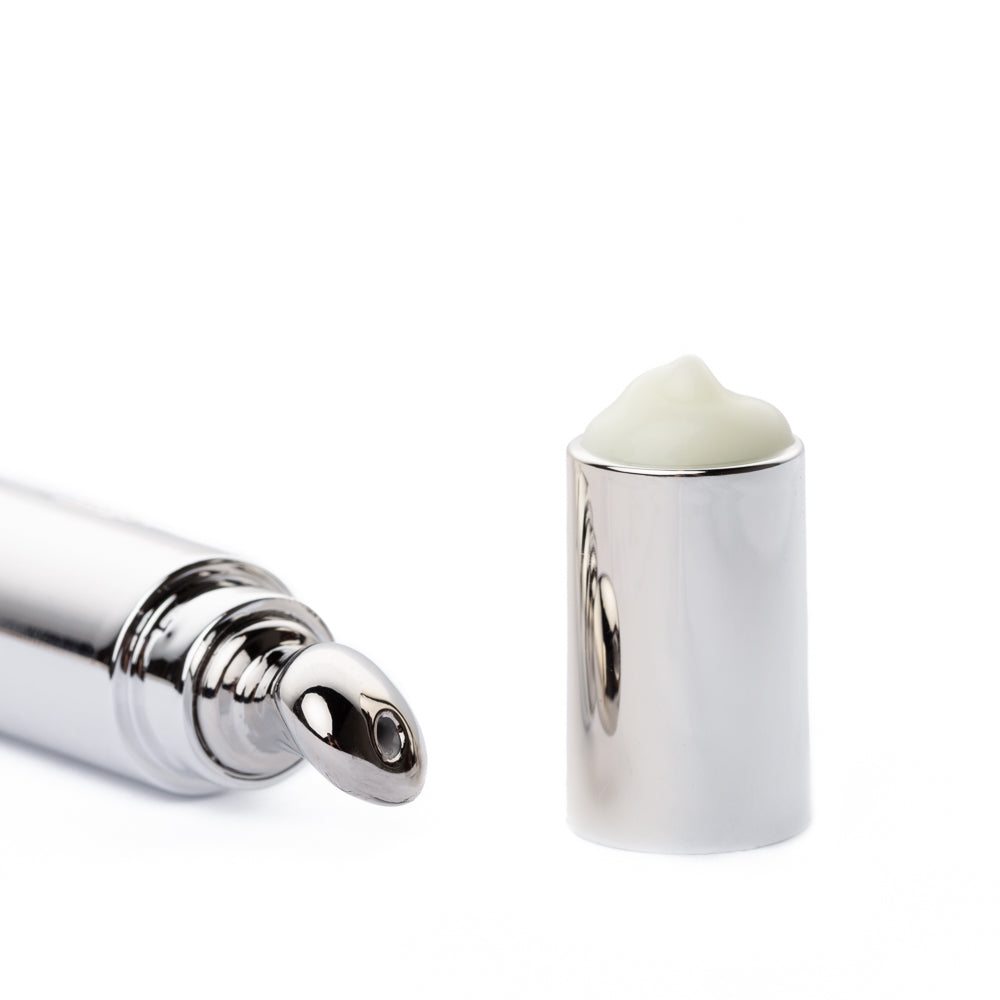 Eye cream roller applicator with pale cream on a silver cap