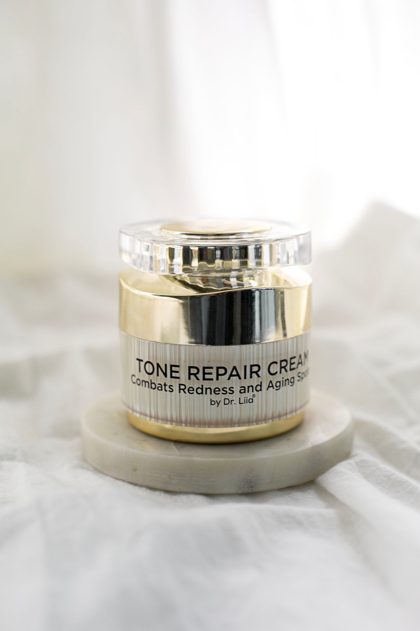 Tone Repair Cream jar on base with gold lid and front label