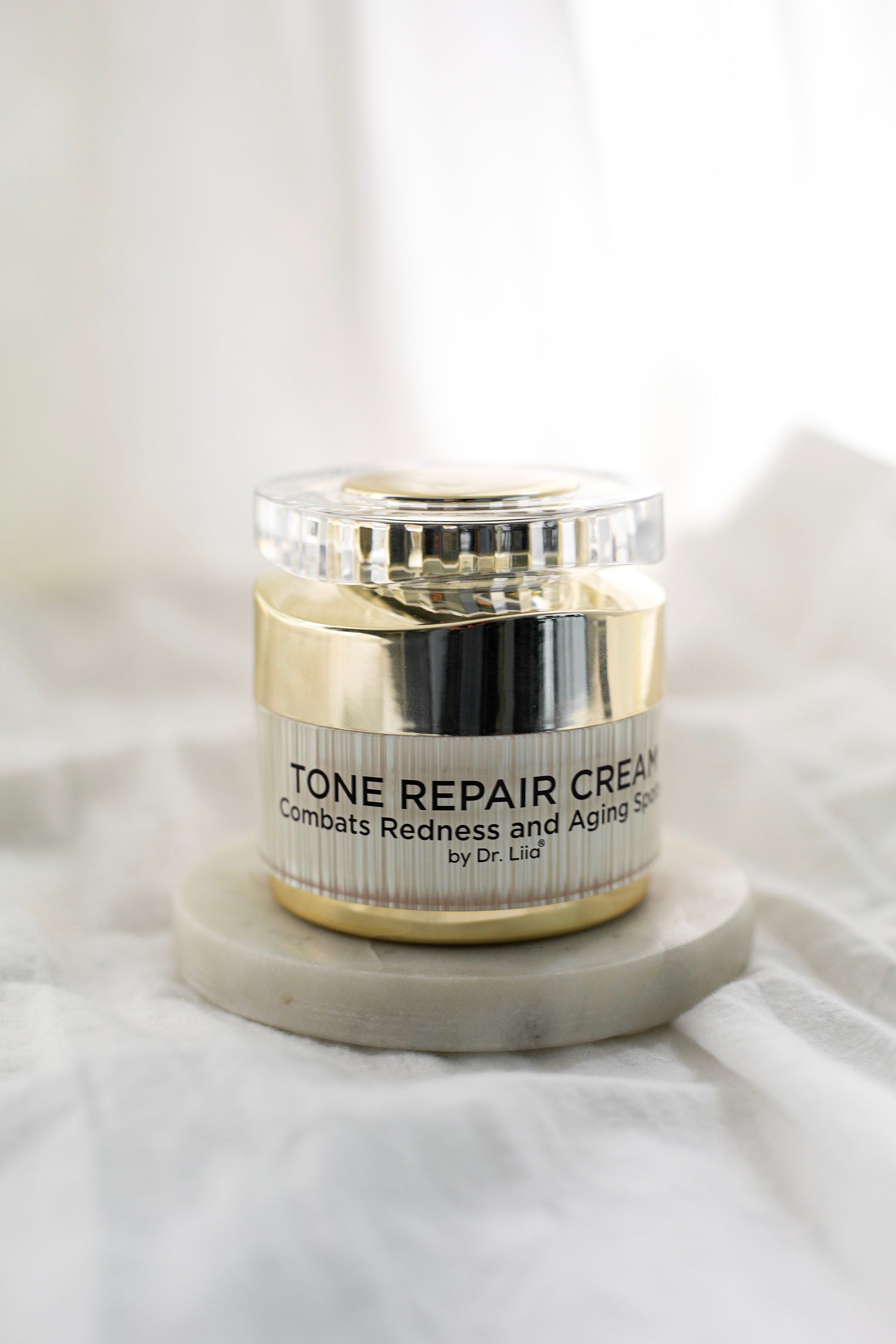 Tone Repair Cream jar on base with gold lid and front label