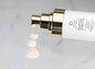 Skincare face scrub cleanser bottle with gold pump and scattered exfoliating beads