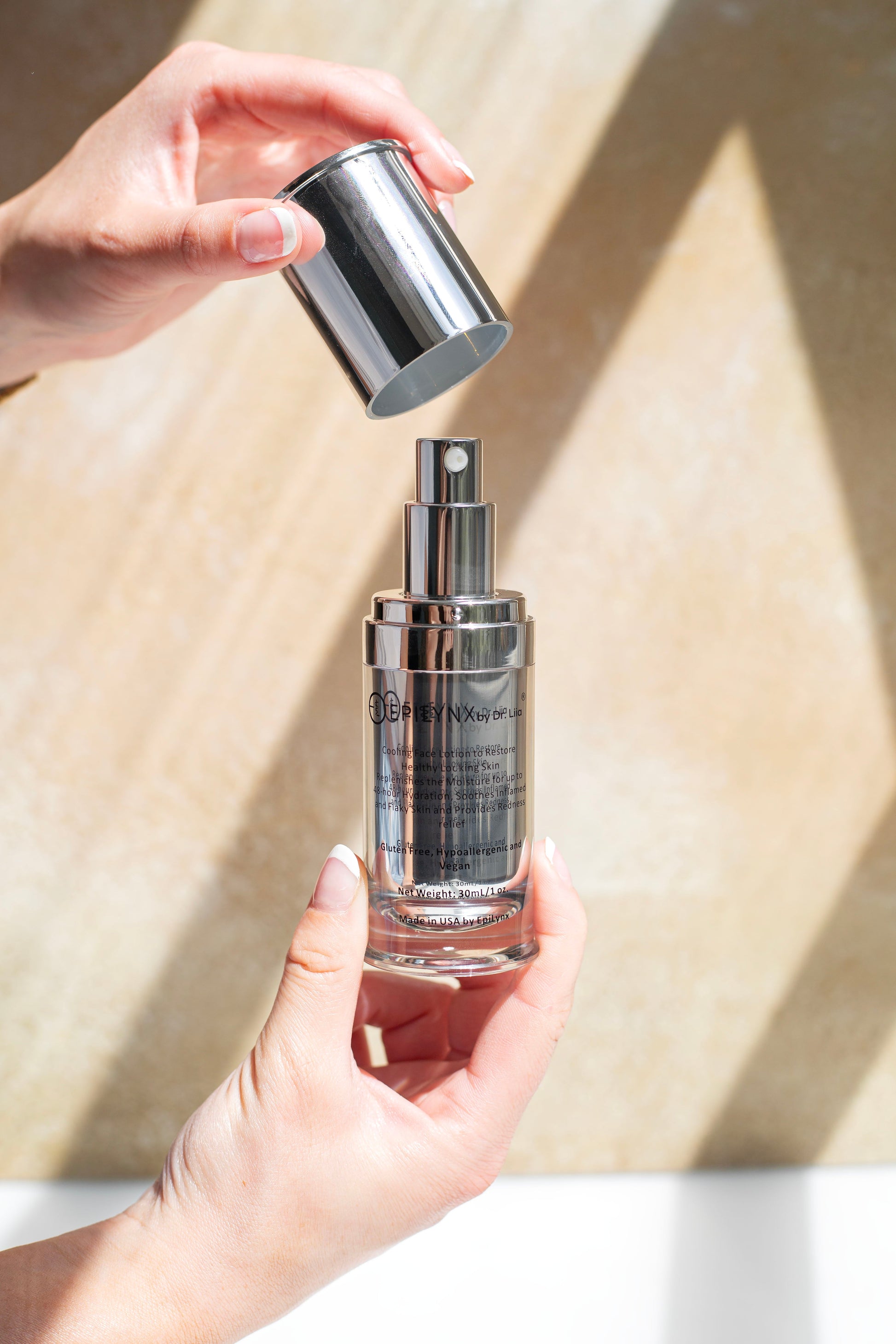 Silver pump moisturizer bottle held in hand with metal cap and clear body