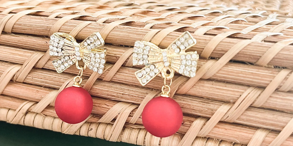 Gold-tone rhinestone bow ornament with two red ball drops, top view