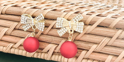 Gold-tone rhinestone bow ornament with two red ball drops, top view