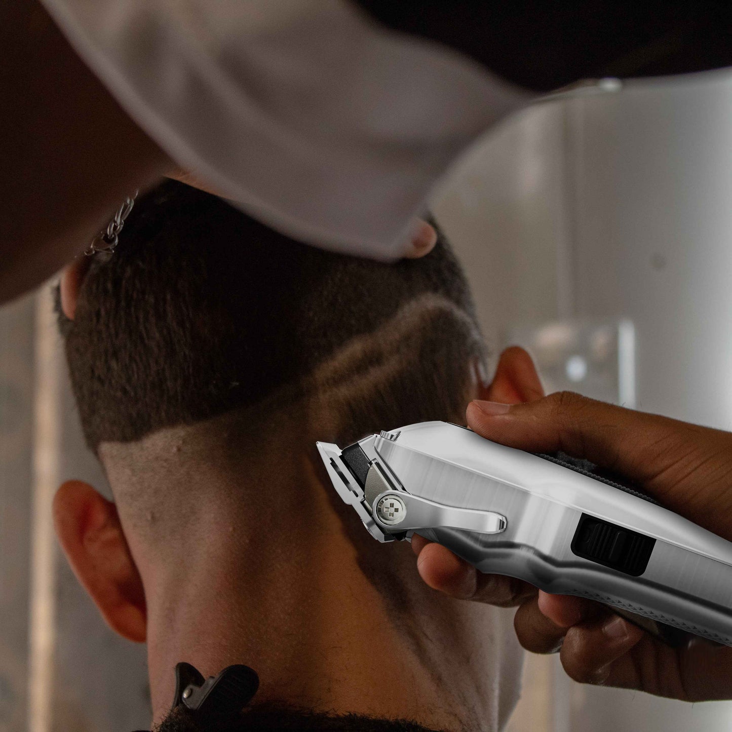 Hair clipper trimming facial hair, silver clipper held against the side of a beard