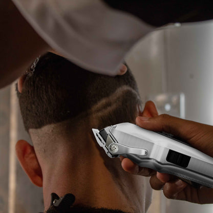 Hair clipper trimming facial hair, silver clipper held against the side of a beard