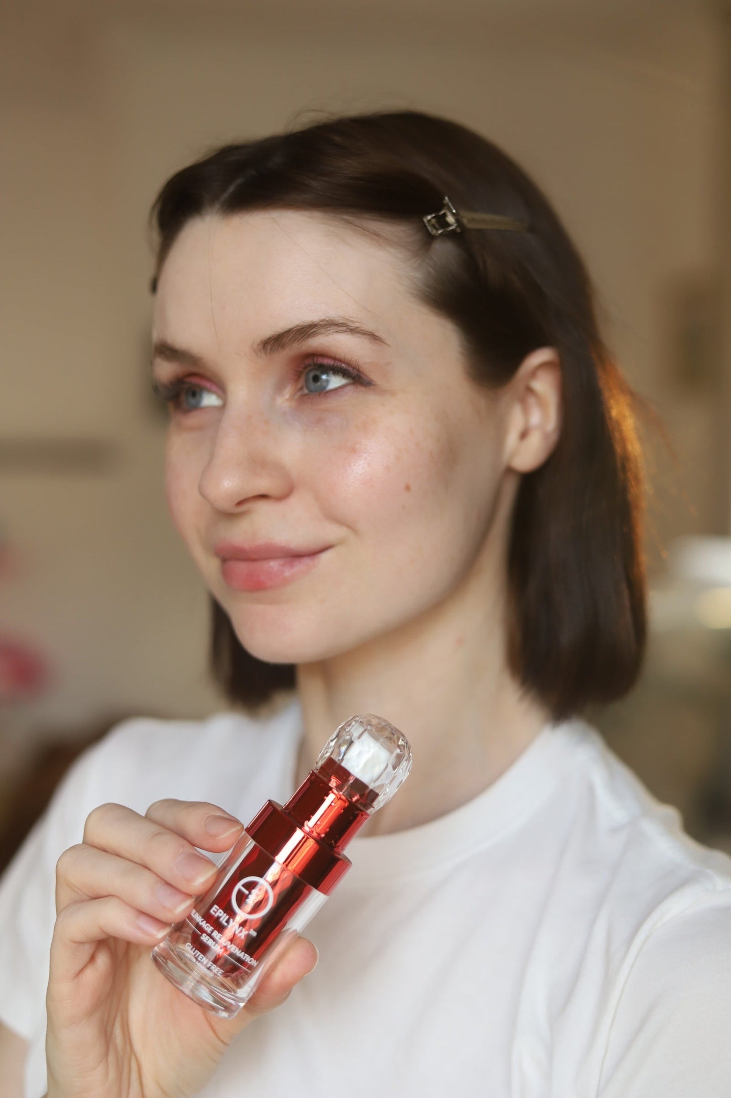 Face serum bottle held by woman near her cheek
