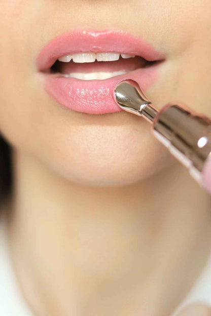 Pink lip gloss being applied with metallic wand on glossy lips