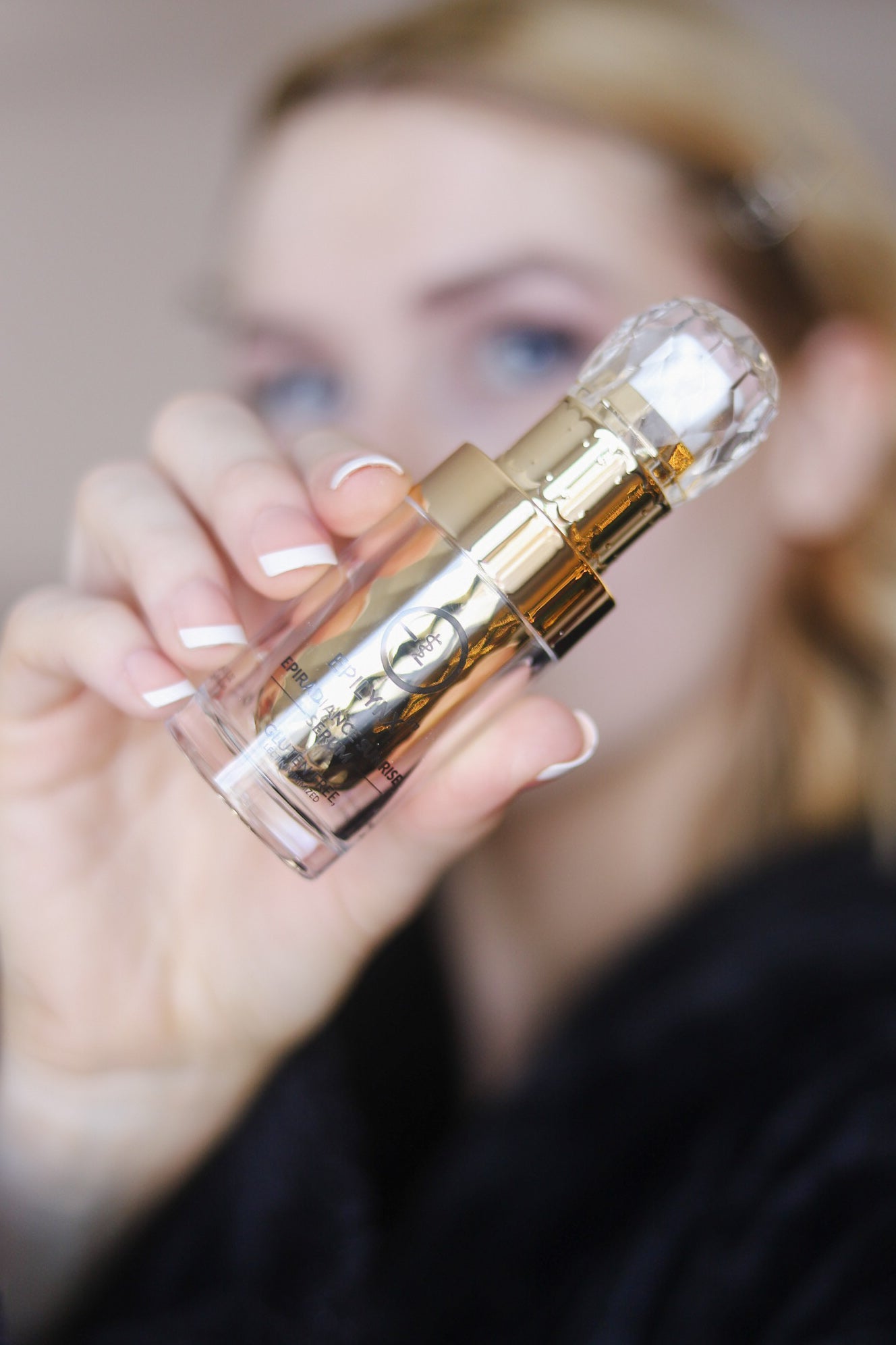 Small clear serum bottle with gold pump and cap held in hand