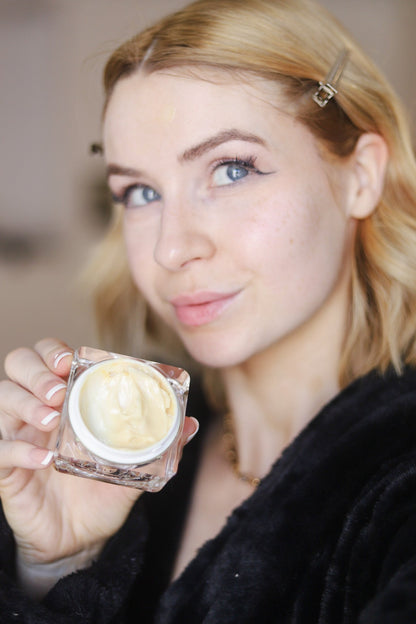 Face cream jar held close with thick gold-yellow cream inside