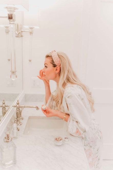 Skincare routine with person applying cream near bathroom sink and faucet