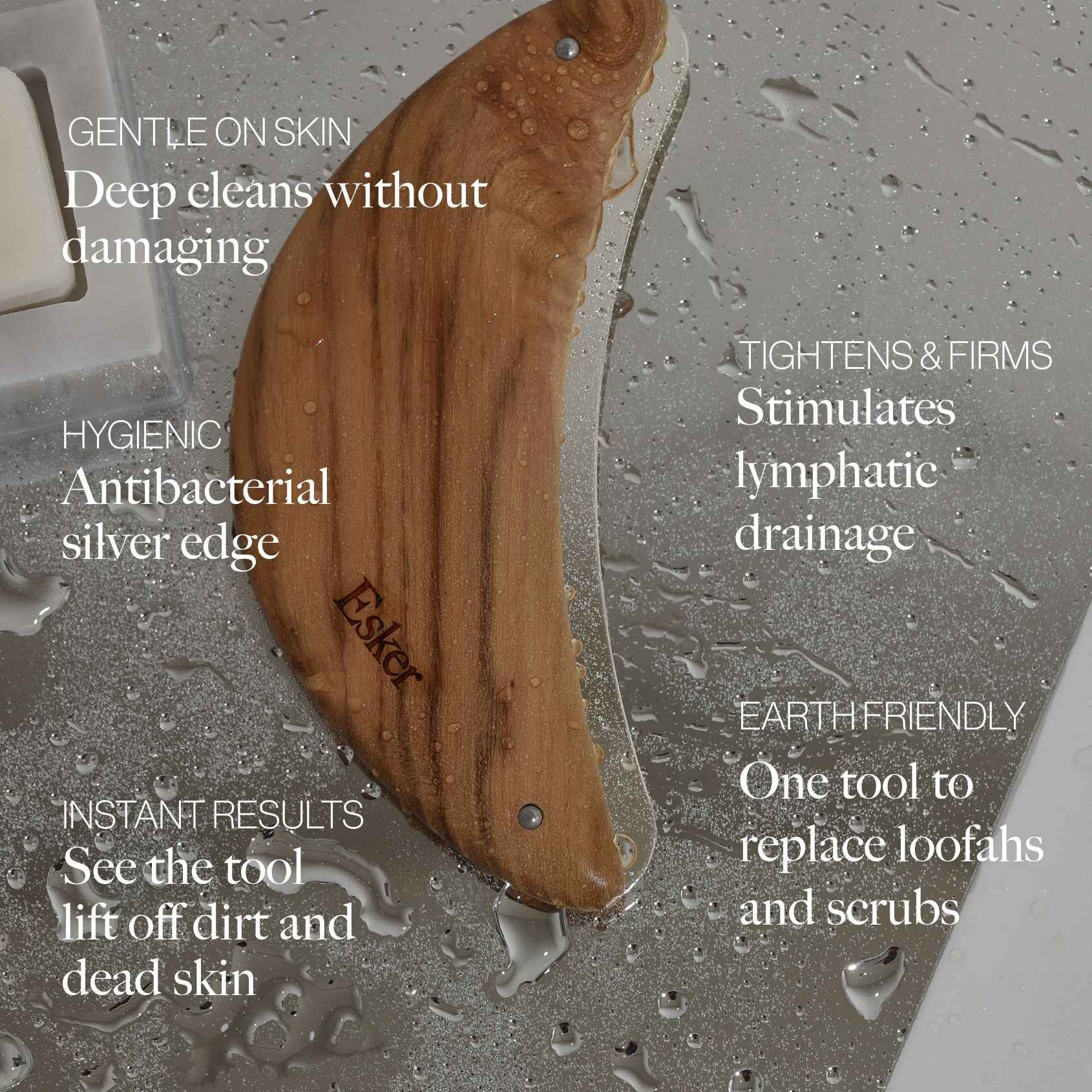 Curved wood body exfoliator tool with silver edge on wet shower surface, droplets visible