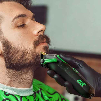 Hair clipper held near beard with black-and-green trimmer head and guard.