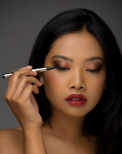 Liquid eyeliner being applied with dark tip along upper lash line