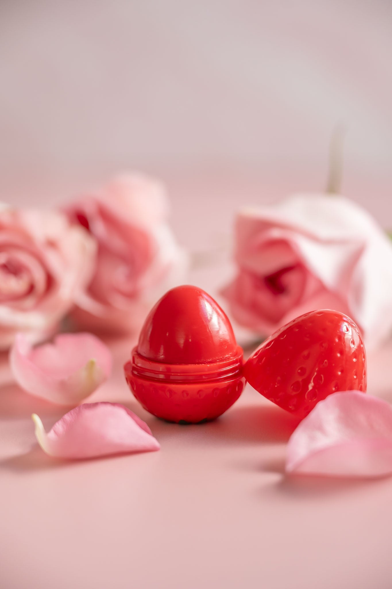 Red strawberry-shaped lip butter balm cups, one with domed cap
