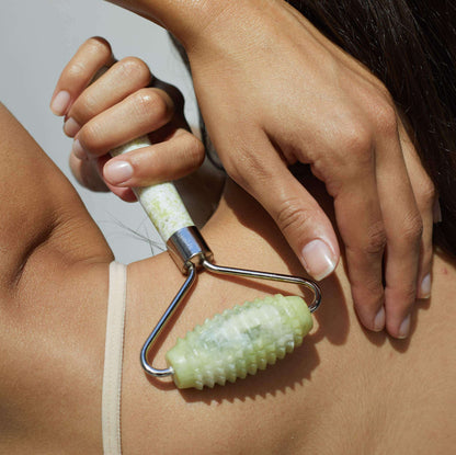 Allover roller used on forearm: textured light-green head and metal handle
