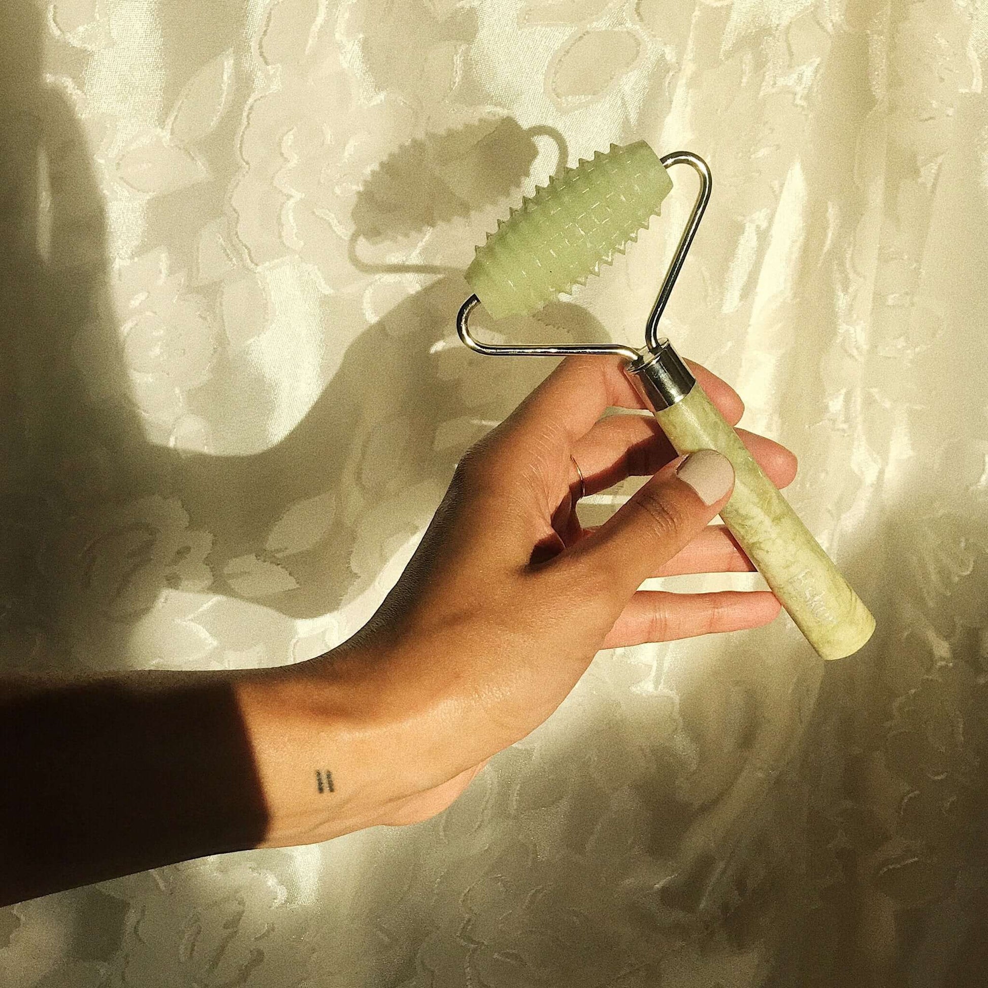 Allover roller rolling on skin with textured light-green head and speckled handle