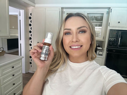 Foaming facial cleanser bottle with white pump held up by a person