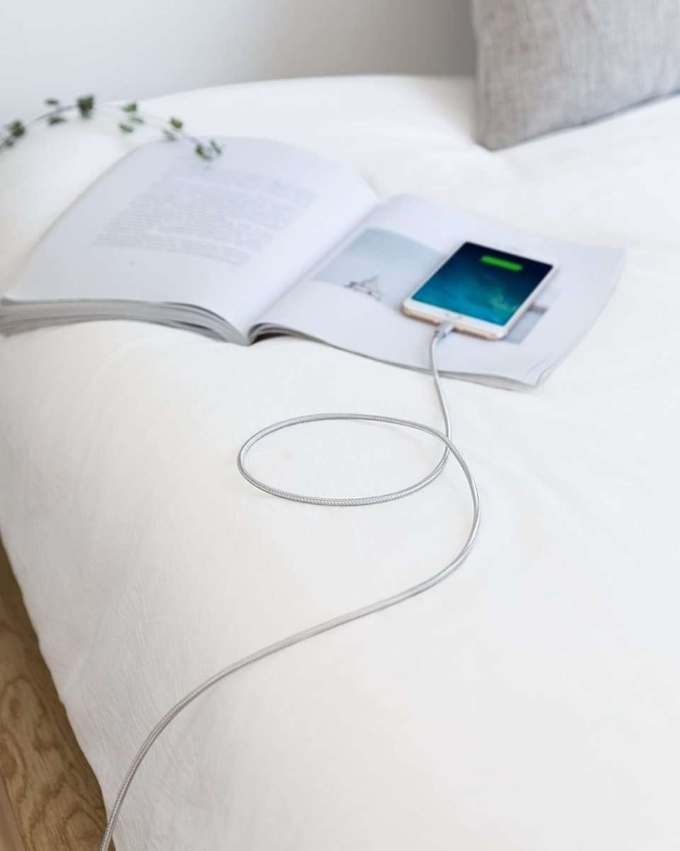 White USB-C to Lightning cable powering a tablet on a table