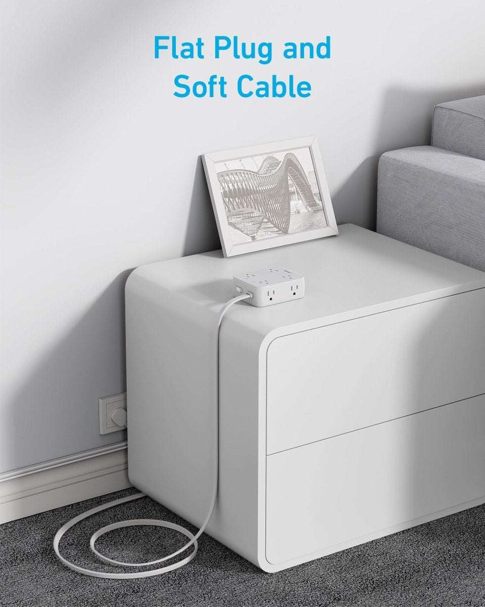 White USB power strip with plug and power cord, near a wall outlet