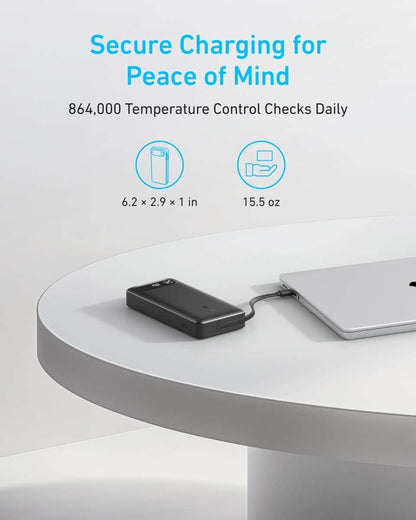 Black power bank with built-in USB-C cable connected to a laptop