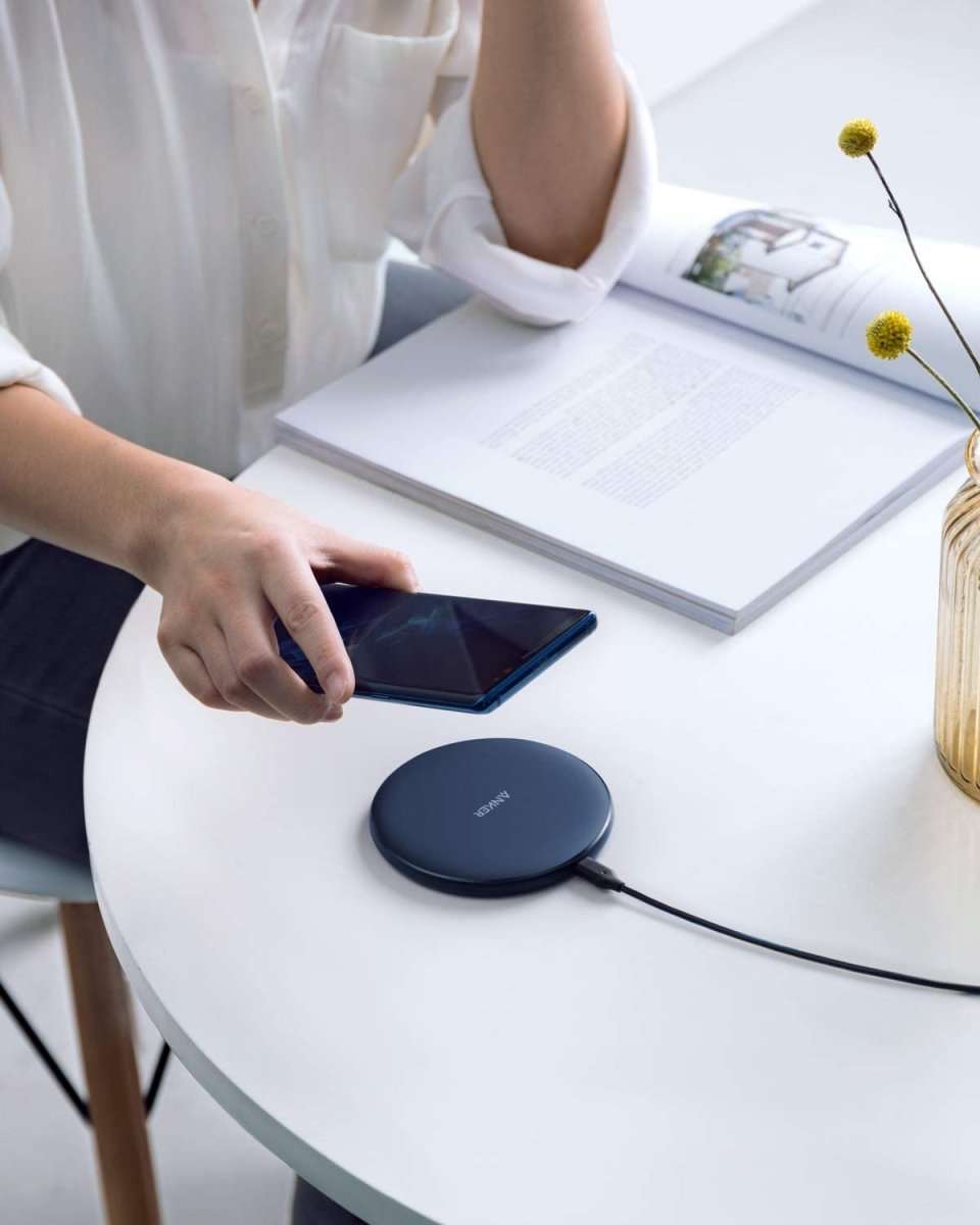 Wireless charging pad on a table with a phone nearby and charging cable attached