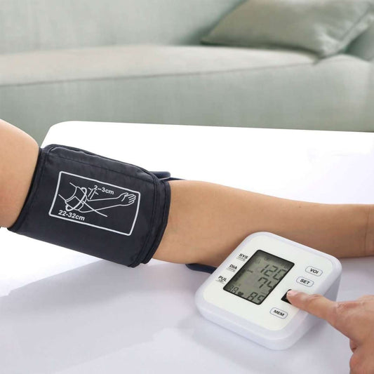 Dark blue arm cuff fitted on upper arm next to white blood pressure monitor display