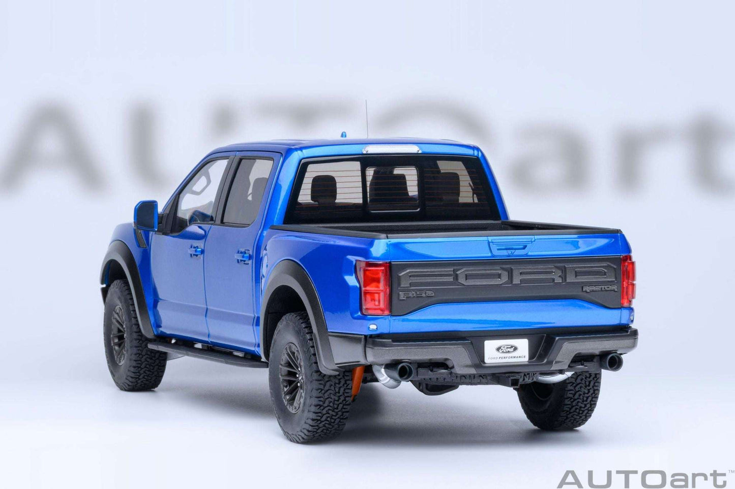 Blue pickup truck model rear three-quarter view with tailgate, exhaust, and off-road tires