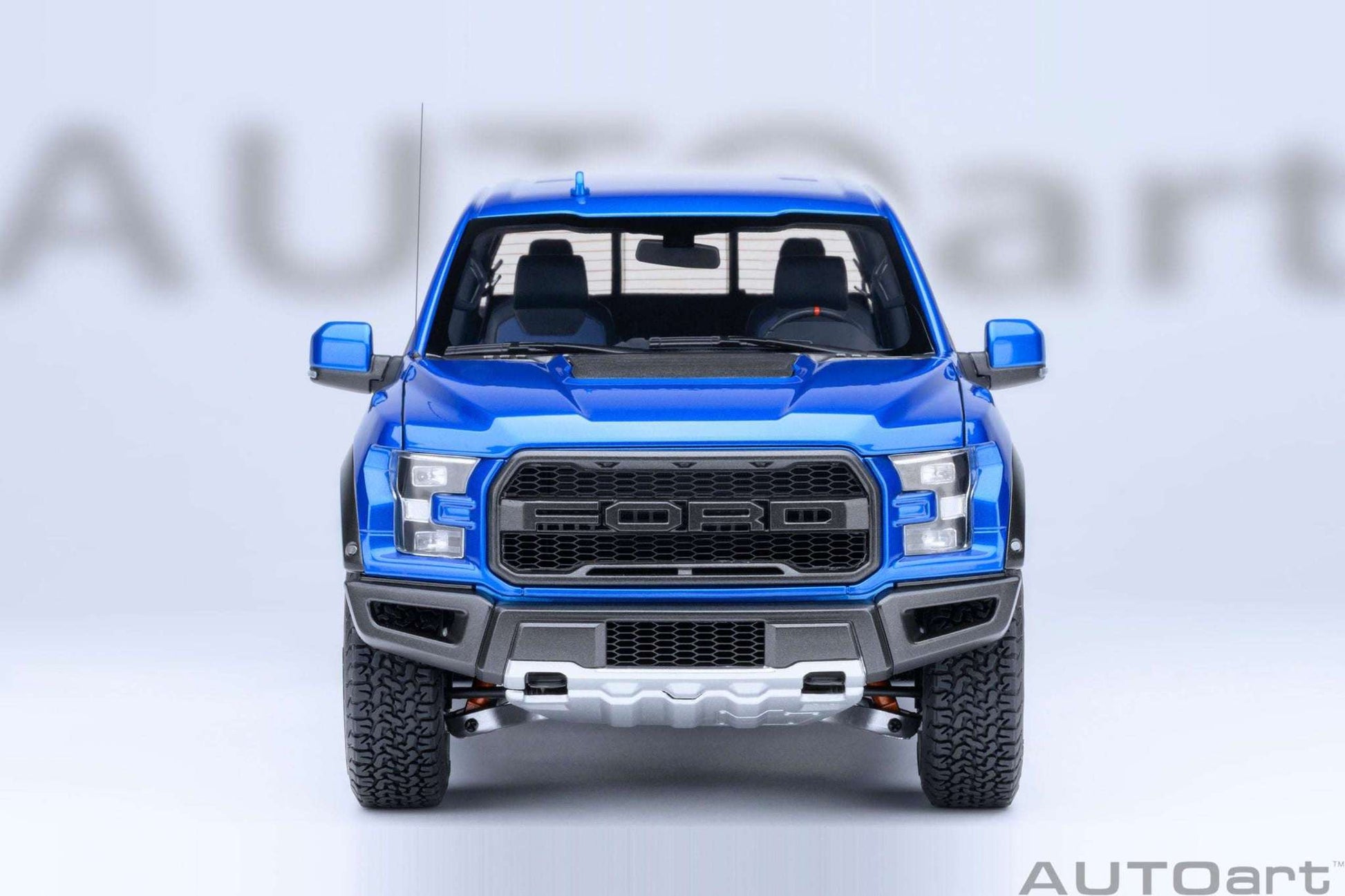 Blue pickup truck model front view with large black grille, fog lights, and knobby tires