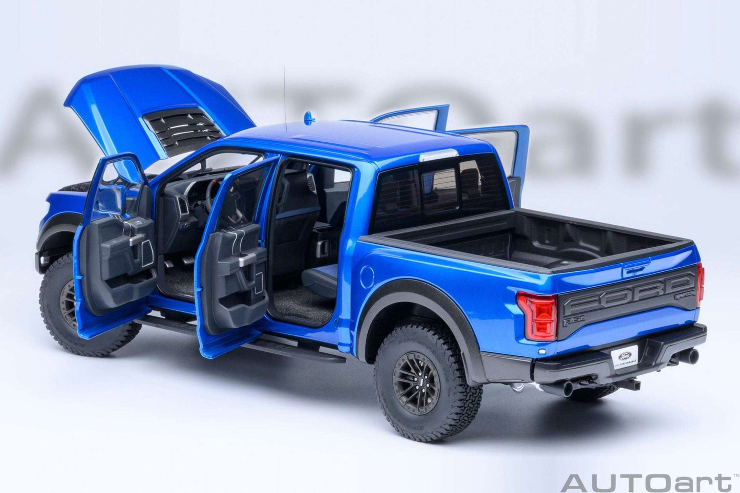 Blue pickup truck model with both doors open, showing dark seats and dashboard detail