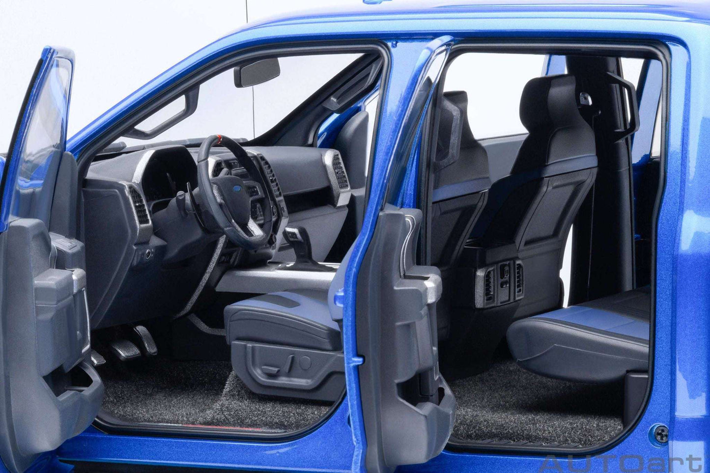 Blue pickup truck model interior with driver seat, steering wheel, and dark floor mat