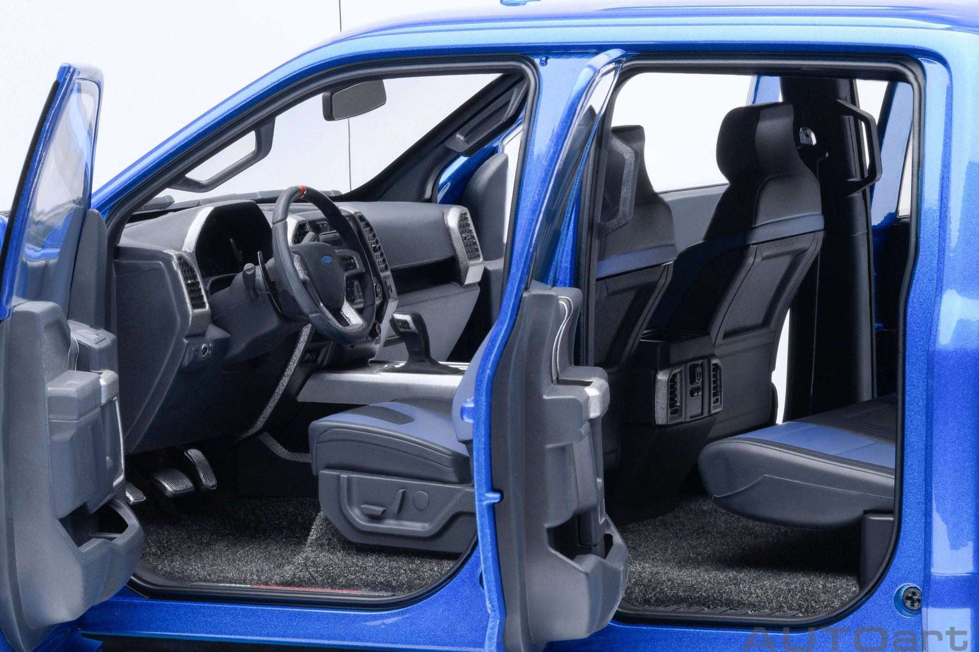 Blue pickup truck model interior with driver seat, steering wheel, and dark floor mat