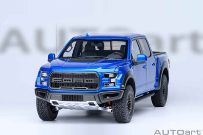 Blue pickup truck model facing forward with black grille, headlights, and textured tires