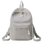 Light gray mini backpack with front panel pocket and tassel zipper pull