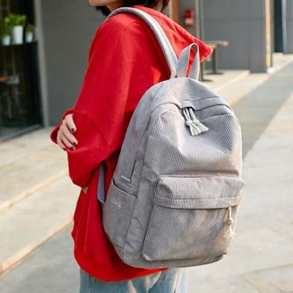 Gray backpack worn on back with tassel drawstring and front pocket