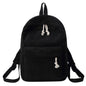 Black backpack with tassel drawstring, front zip pocket, and adjustable shoulder straps