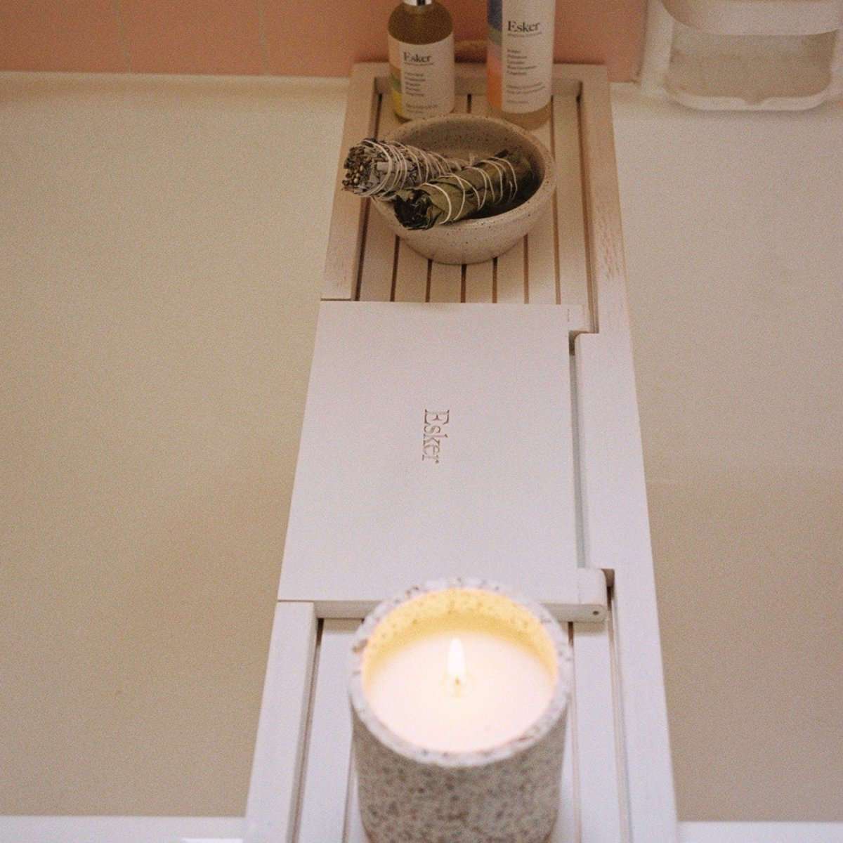 Bath board with white frame and inner center shelf, candle on top.