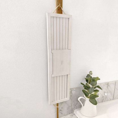 Bath board with white slatted panels and hanging loop, folded open against a wall.