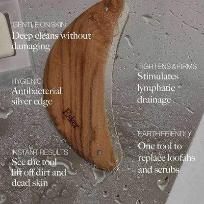 Wooden body exfoliator tool on wet surface with silver edge and rivets