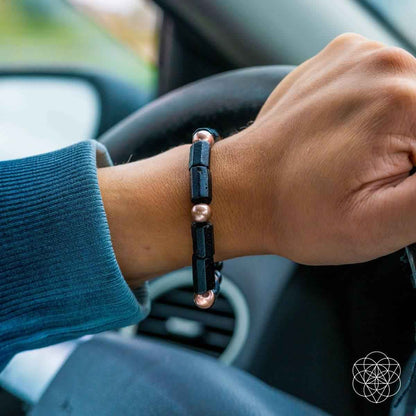 Copper-tone and black beaded bracelet on hand with rectangular dark spacer beads