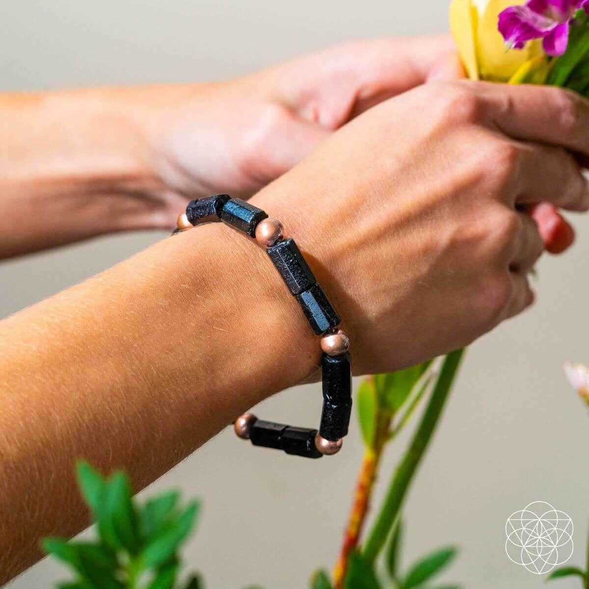Copper-tone and black bracelet on wrist with rectangular dark spacer beads