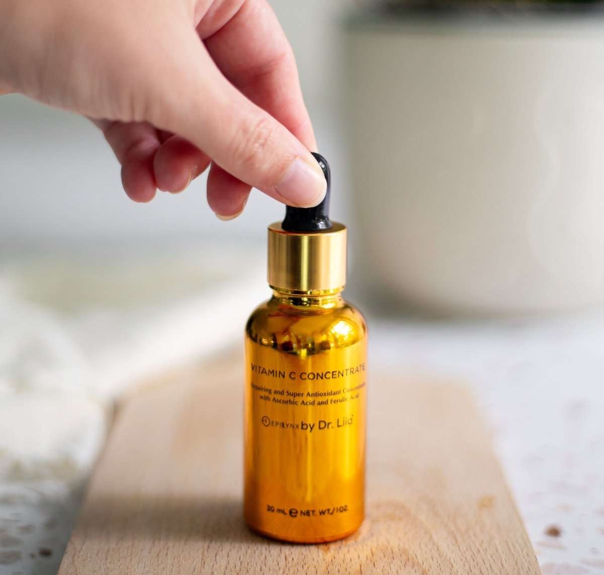 Amber serum bottle with black dropper tip held above the bottle