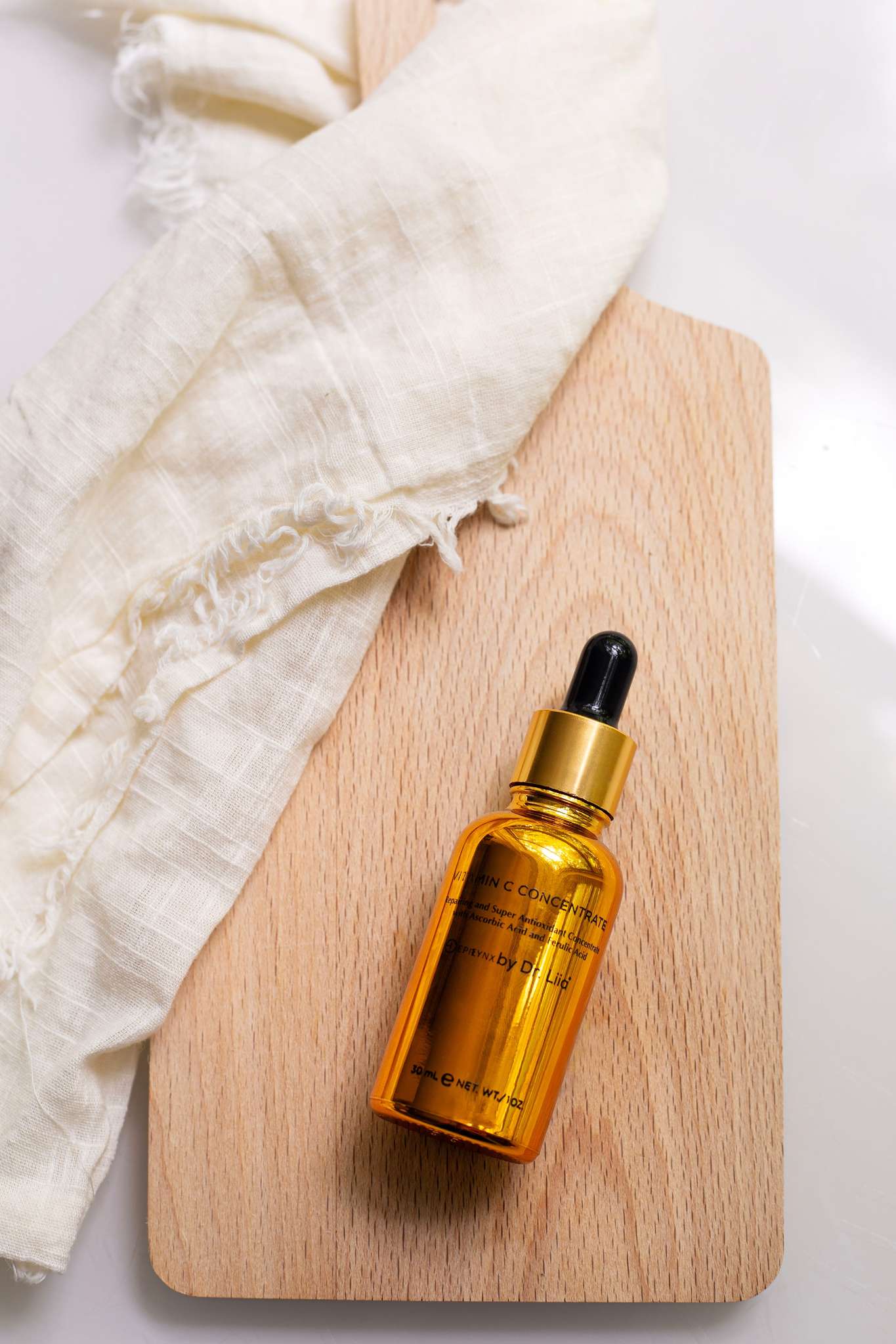 Amber vitamin C glow serum bottle with black dropper and gold cap