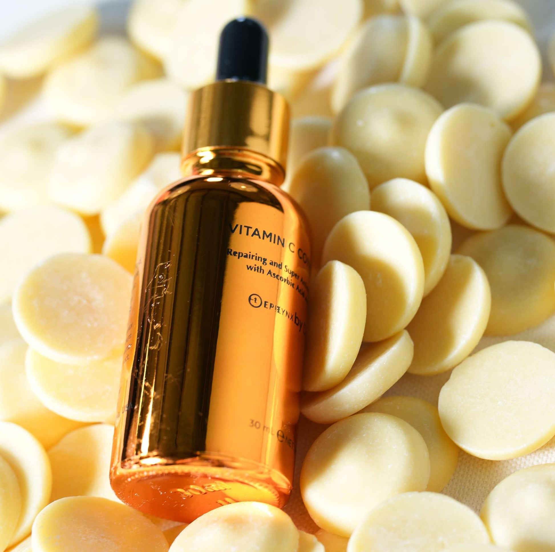 Amber vitamin C serum bottle with black dropper among pale yellow capsules