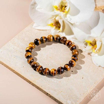 Tiger's eye bead bracelet with round striped beads laid on a stone surface.