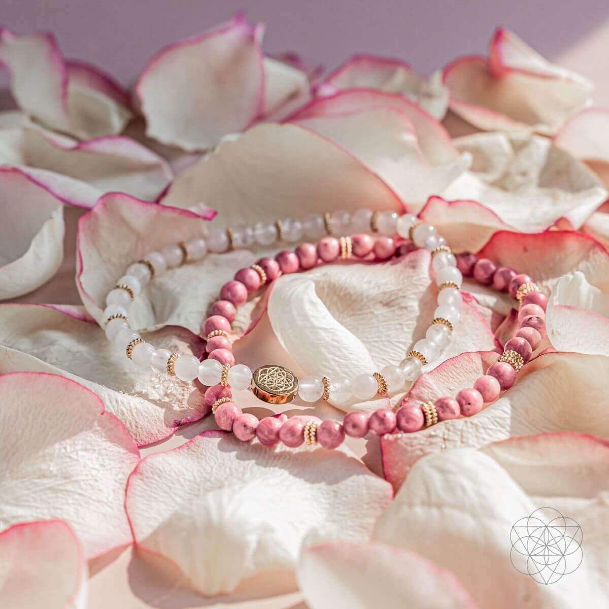 Four layered beaded bracelets in pink and white with a gold-tone medallion charm