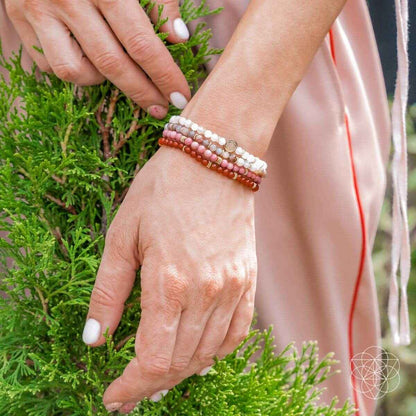 Red, pink, and white bead bracelet worn on wrist with layered beaded strands
