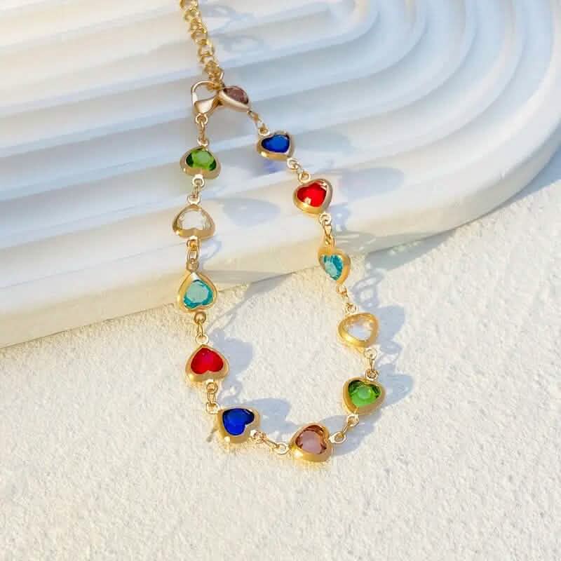 Gold-tone heart charm bracelet with multicolor stones and dangling heart links