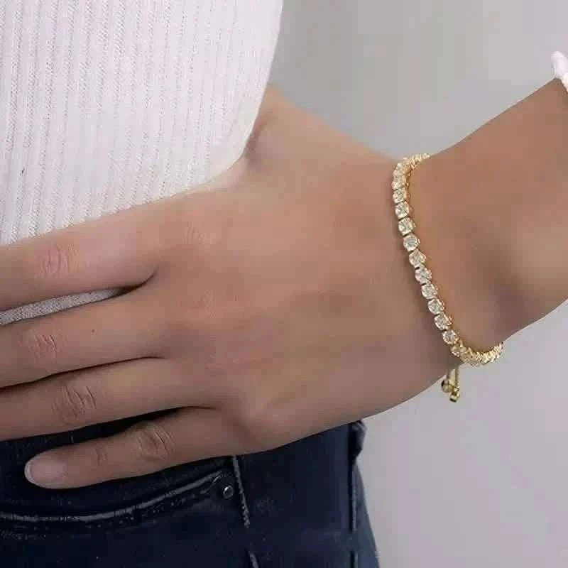 Gold-tone tennis bracelet worn on wrist with a row of clear stones