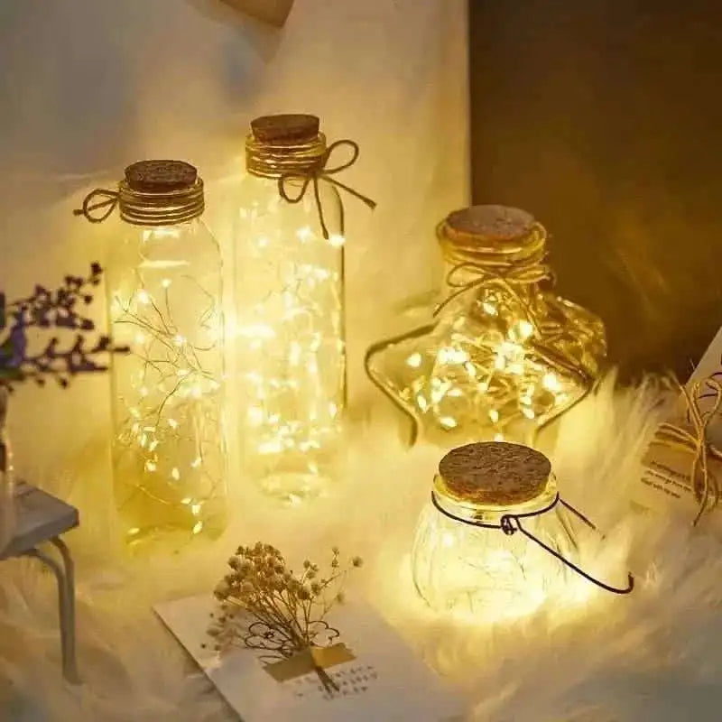 Warm white LED string lights inside small glass jar lamps with wire.
